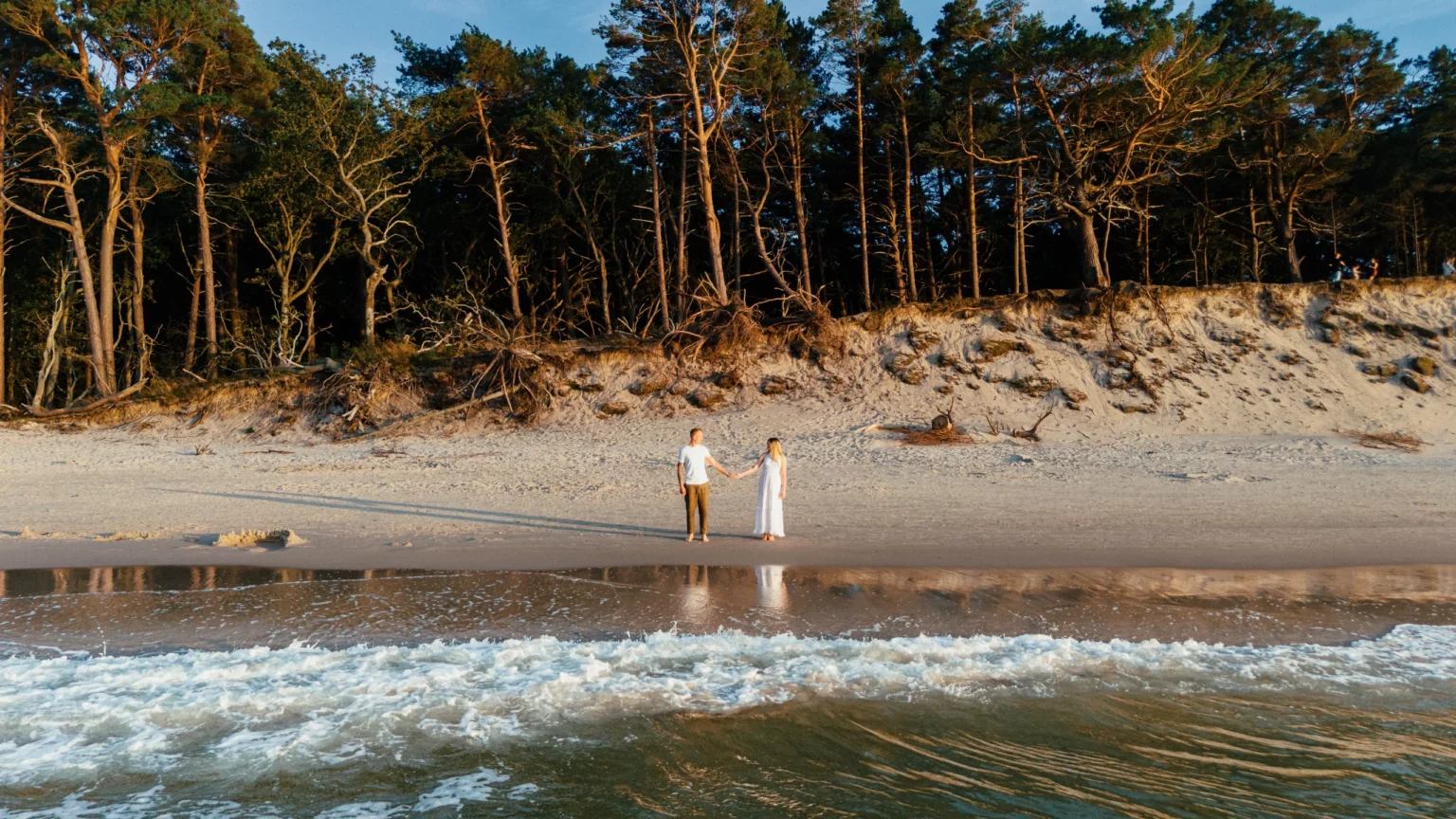 Nadia i Michał — para młoda na plaży pod sosnowym lasem.