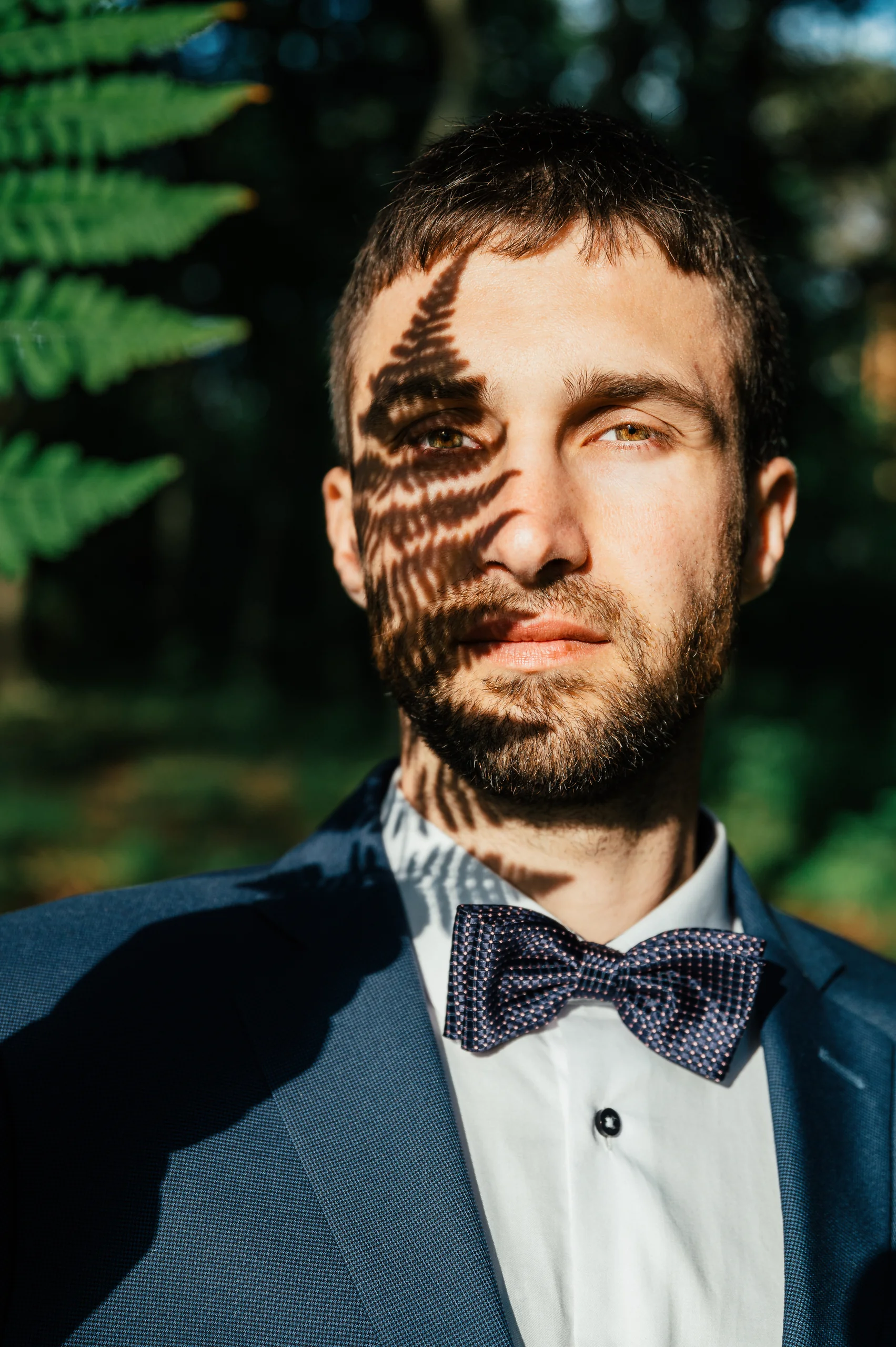Portret pana młodego wśród zielonych liści.