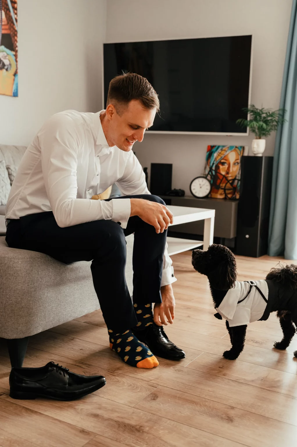 Karolina i Sebastian — pan młody przygotowuje strój w towarzystwie psa.