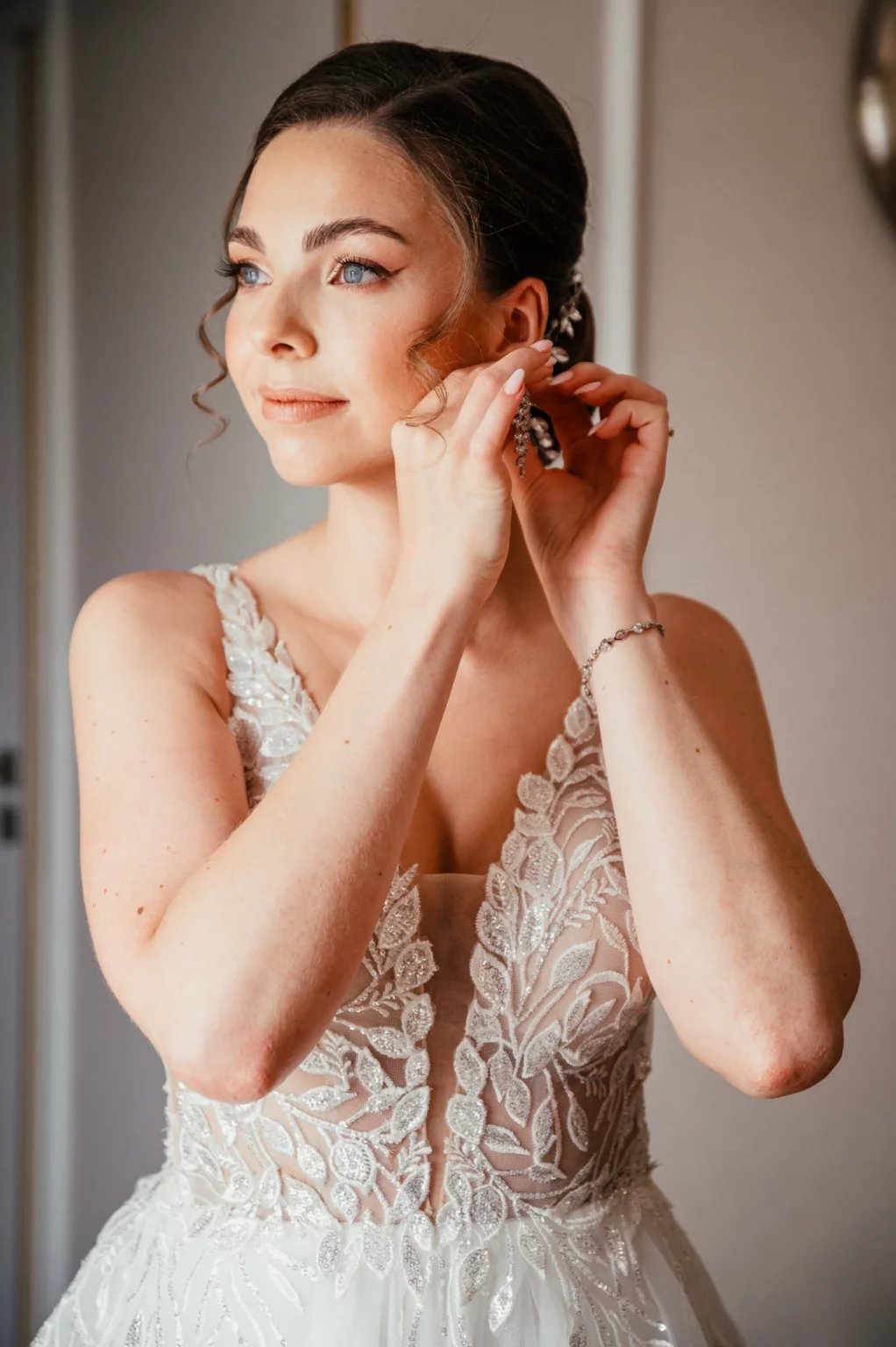 Karolina i Sebastian — panna młoda zakłada kolczyk.