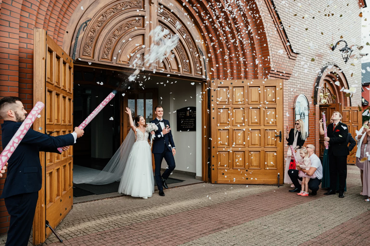 Karolina i Sebastian — nowożeńcy w drzwiach świątyni.