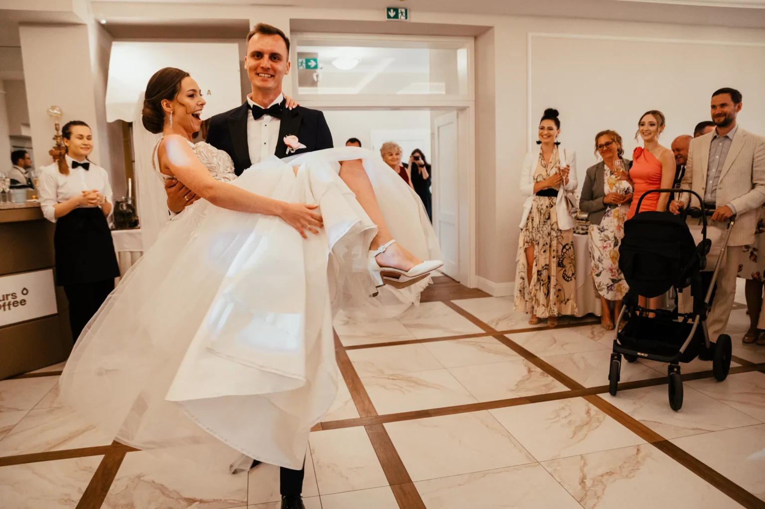 Karolina i Sebastian — pan młody niesie pannę młodą na rękach.