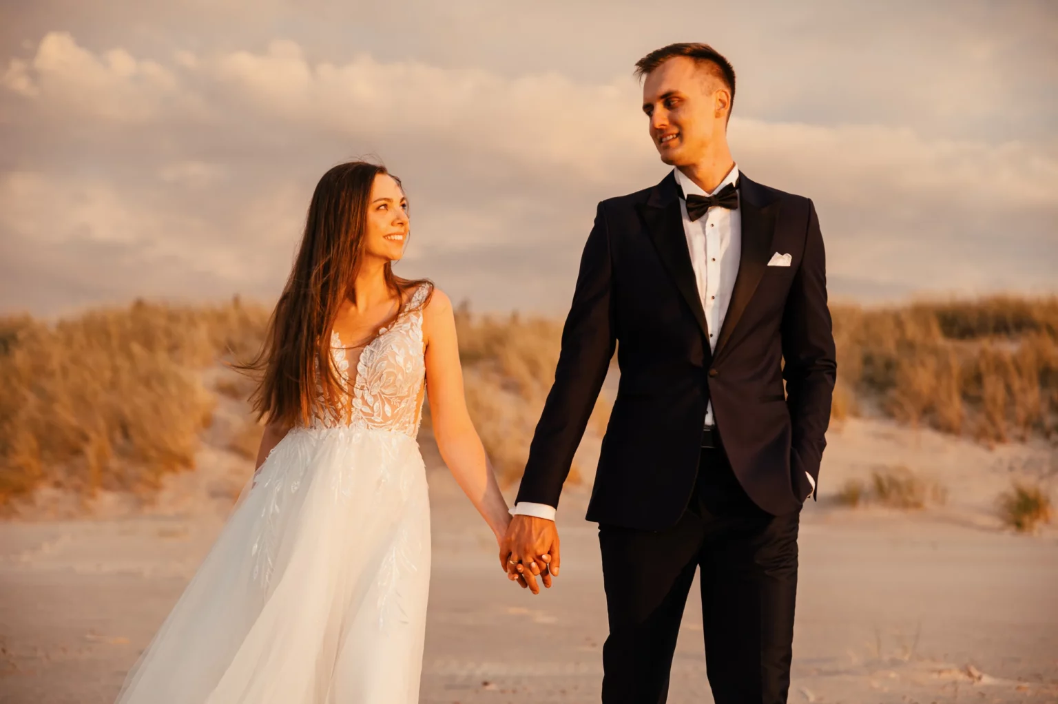 Karolina i Sebastian — para młoda trzyma się za ręce na plaży.