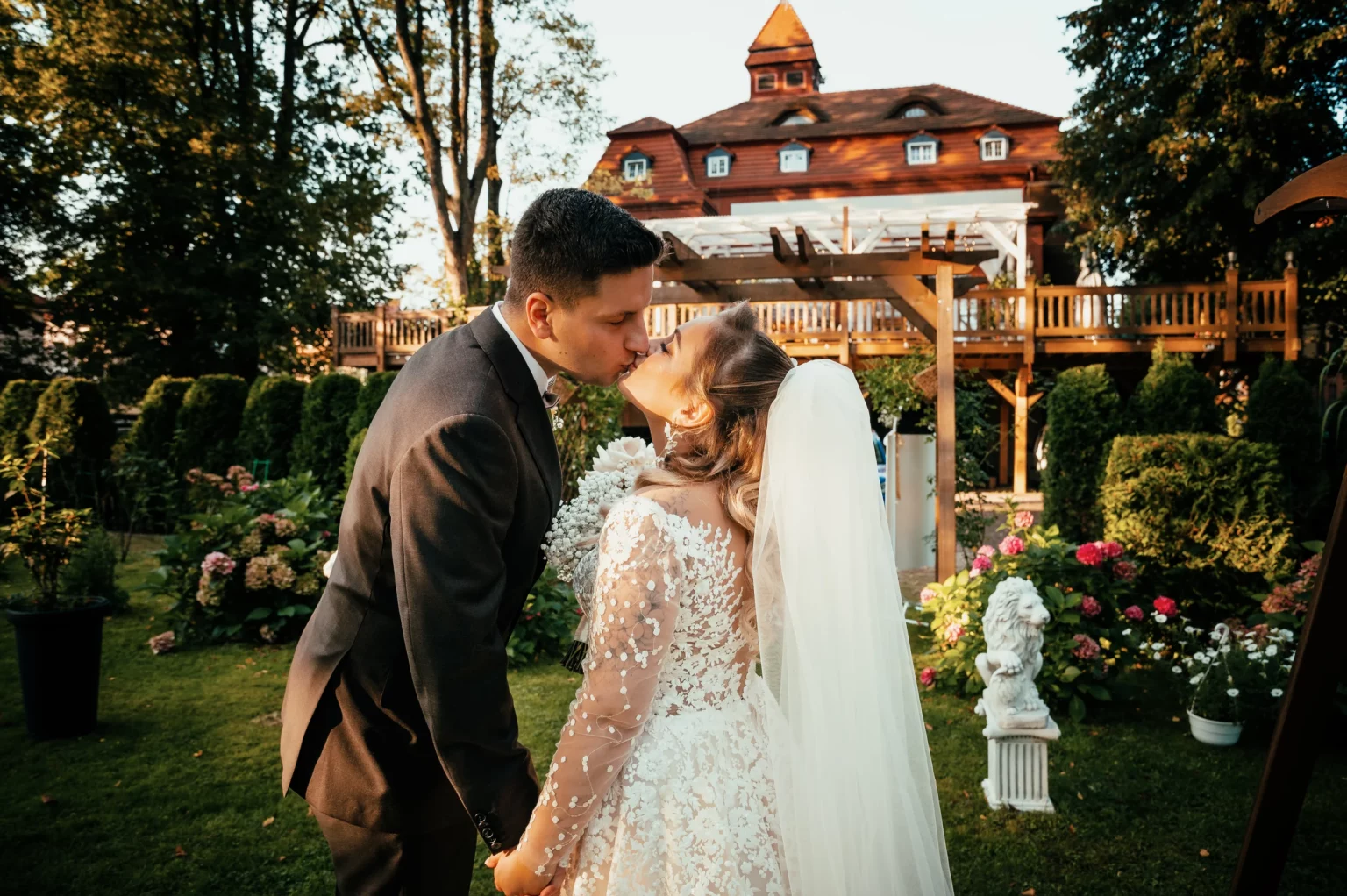Kasia i Radek — pocałunek pary młodej w ogrodzie.