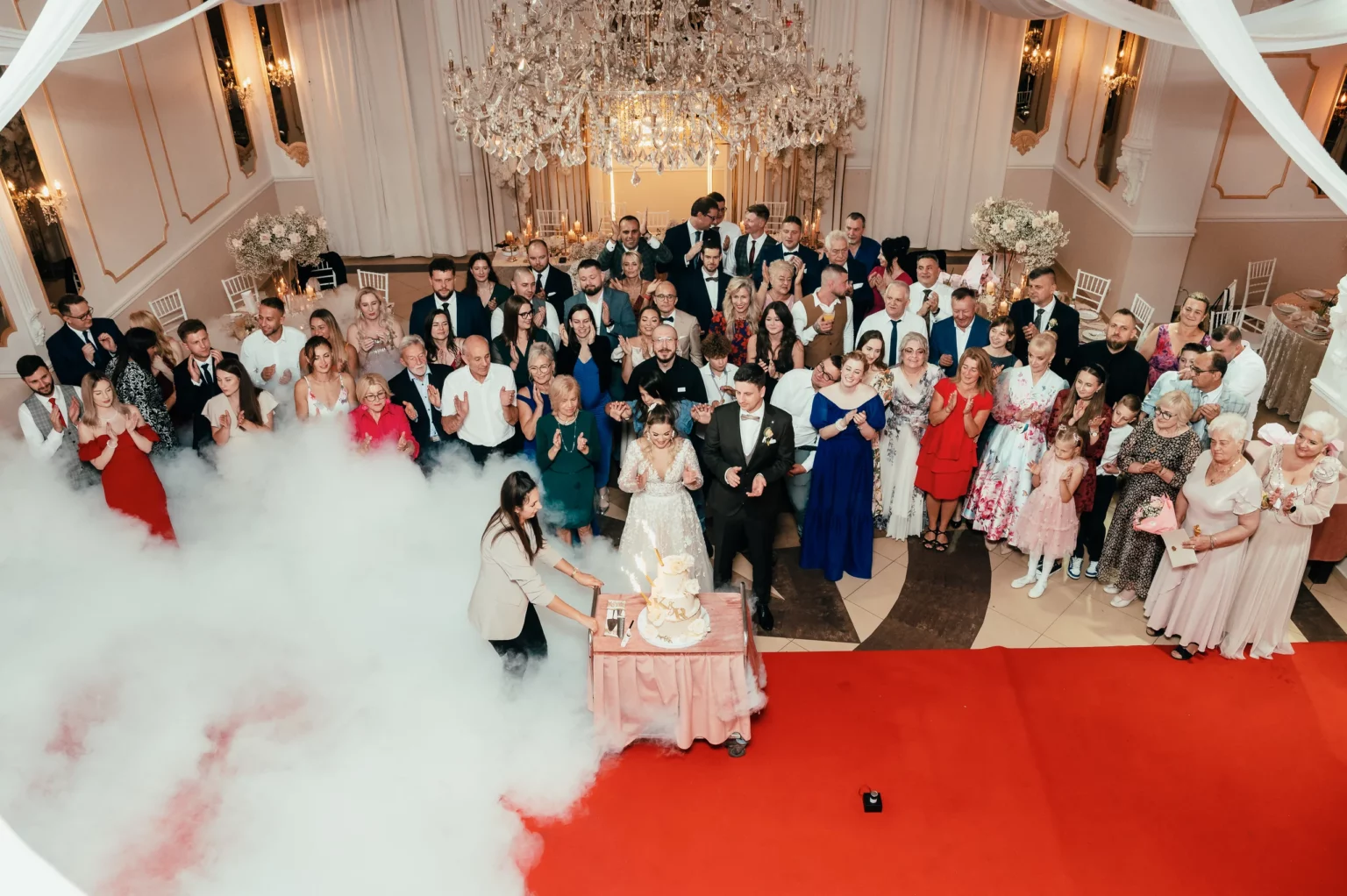 Kasia i Radek — goście otaczają parę młodą przy torcie.