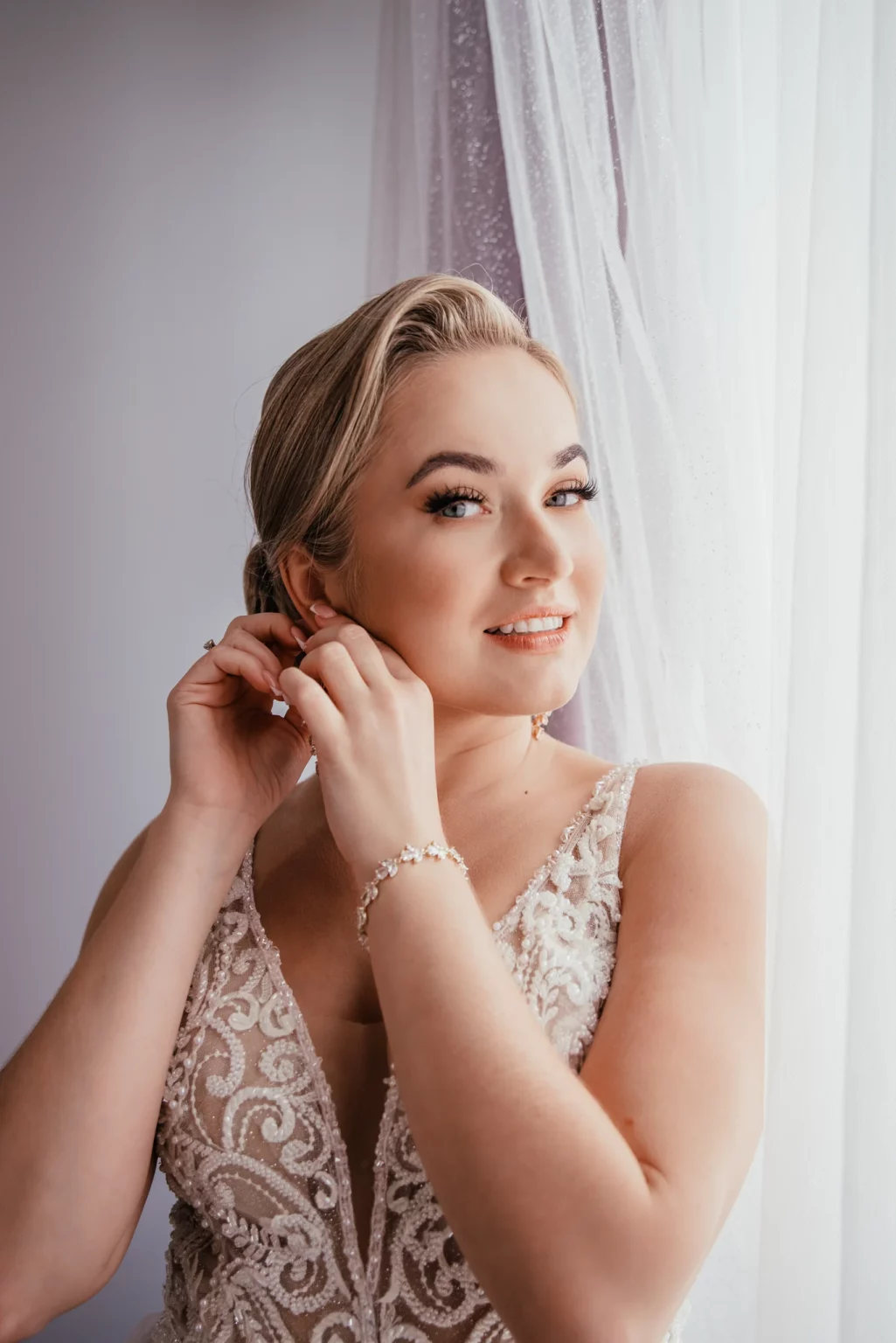 Paulina i Rafał — panna młoda zakłada kolczyk.