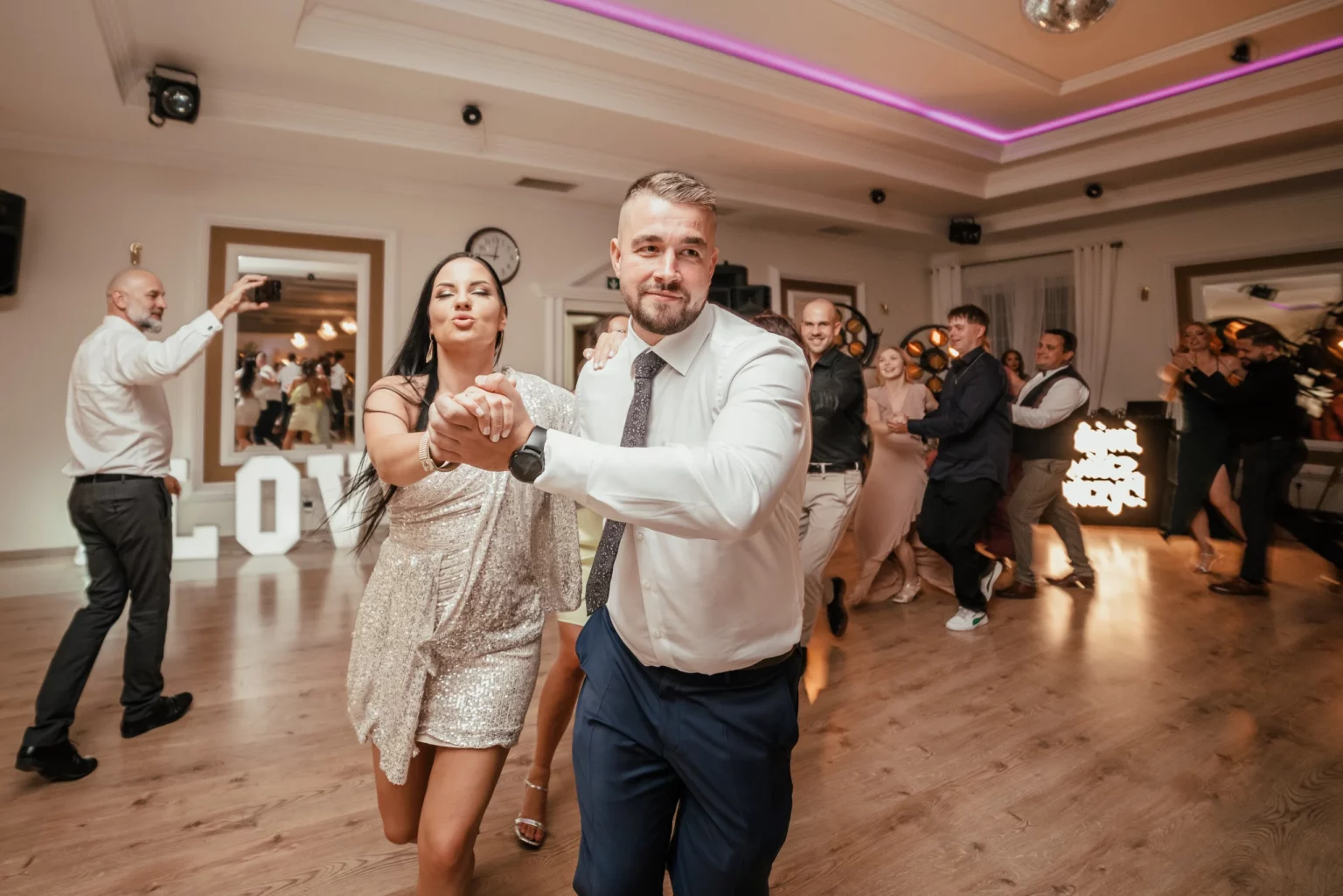 Paulina i Rafał — pan młody niesie gościnię podczas zabawy.