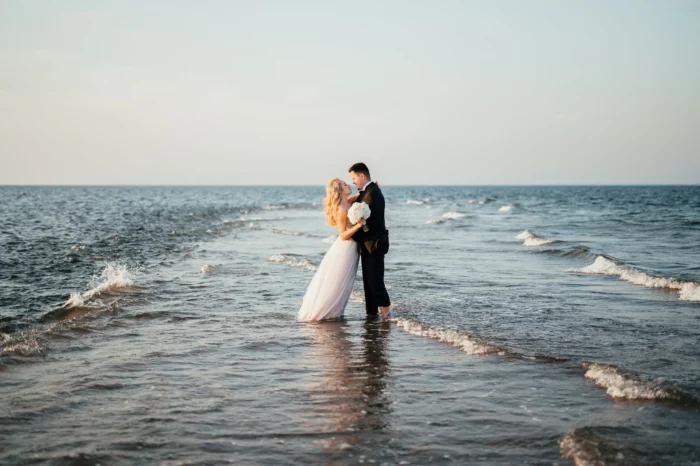 Para młoda stojąca przy falach na plaży.