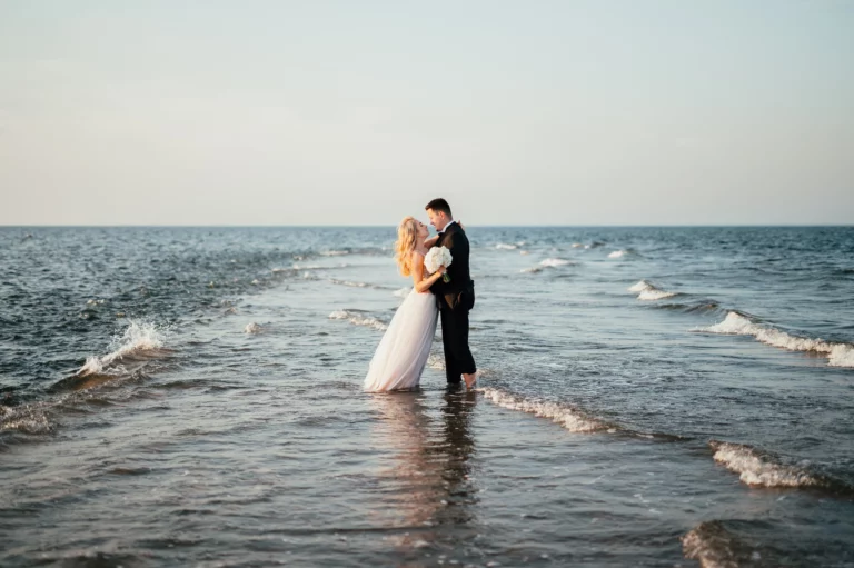 Para młoda stojąca przy falach na plaży.