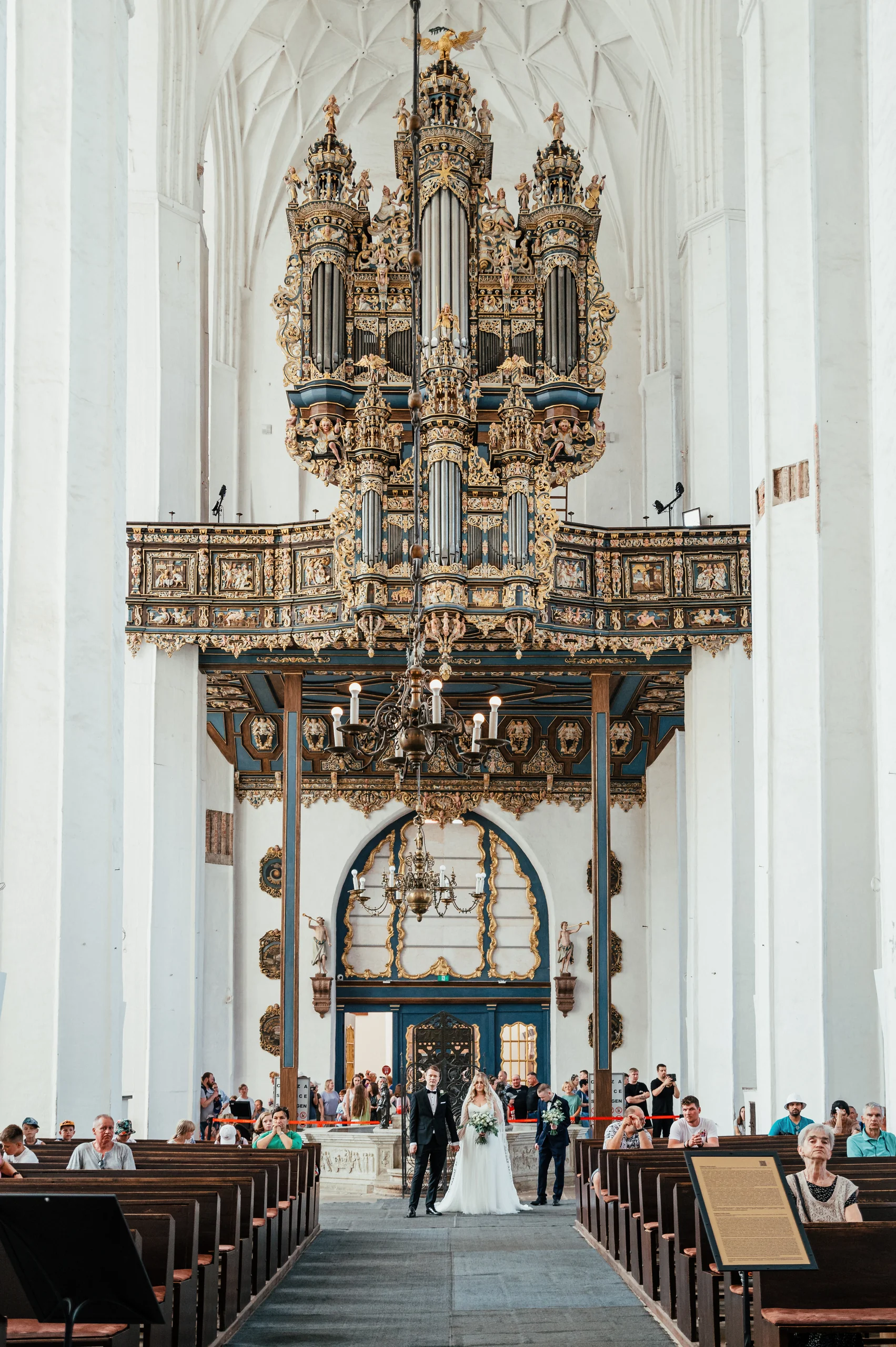 Ceremonia ślubna we wnętrzu kościoła z wysokim ołtarzem.